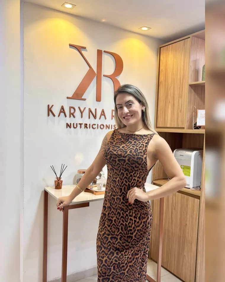 Karyna Rios no consultório, com o logo KR na parede